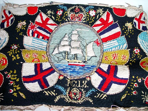 A British Woolwork Picture of a Ship Surrounded by Flags, early 20th century. SOLD •